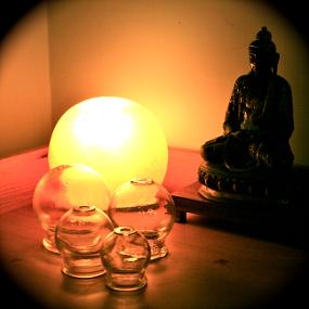 Statue of Buddha, surrounded by cupping for Traditional Chinese Medicine therapy. Globe light is on  